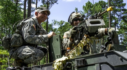 New York State Command Sgt. Major David Piwowarski the senior enlisted advisor to the New York Army National Guard speaks with Pfc. Mathew Smithers a cavalry scout with the 2nd Squadron 101st Cavalry while atop a Humvee and manning a .50-caliber machine g
