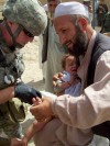 Specialist Daniel Covel from Marion, NY treats the badly burned leg of a young Afghan boy.