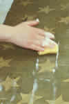 The flag is cleaned with a surfactant (detergent) in water to remove the loosened and water-soluble soils using a suction table.
