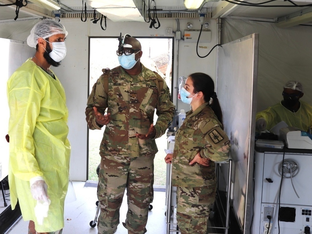 
                From left to right, South African Military Health Service Dentist, Maj. W.A. Mustafa speaks with counterparts from the Army Reserves and the New York Army National Guard. Dentist Maj. Dwayne Bodie and Dental Technician Staff Sgt. Christine Iraci on July 13th outside of Richards Bay, South Africa. The 2022 exercise of Shared Accord is the fourth, with previous iterations in 2011, 2013, and 2017. Apart from the 2017 exercise at the Army Combat Training Centre in the Northern Cape, the Eastern Cape hosted the other two, with a humanitarian and healthcare focus on rural, local communities. A planned 2020 Shared Accord fell victim to the worldwide COVID-19 pandemic. Courtesy, Photo Asset.            
