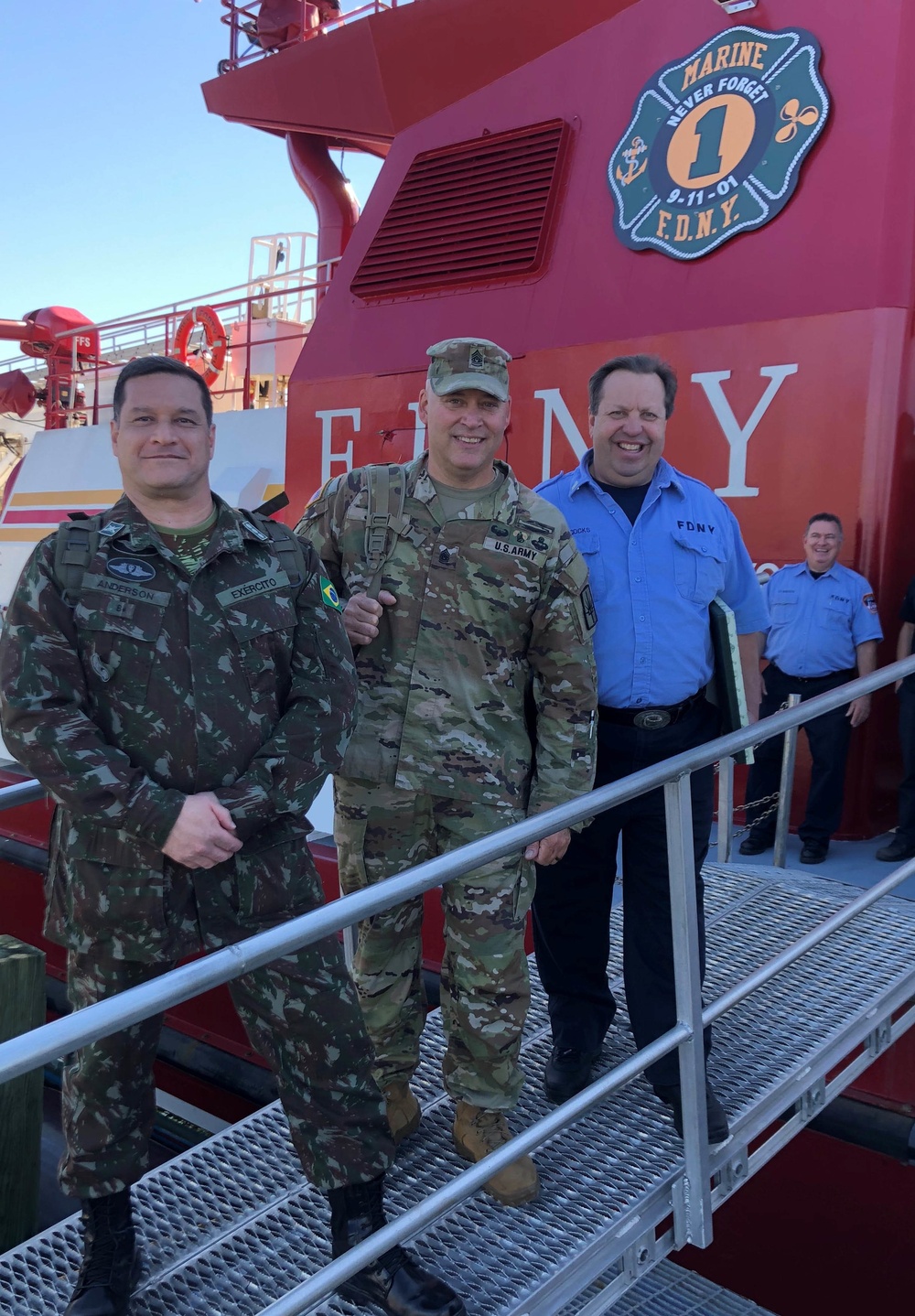
                Brazilian Army Col. Anderson Pedreira Silva, and Army Sgt Major Robert Jenks, New York Army National Guard, pose with a New York City firefighter on board one of the city's fire boats during a National Guard State Partnership Program visit to the Fire Department New York's Randall's Island training site in New York City on October 20 2021. Pedreira Silva has now retired from Brazil's army but will continue to work as a civilian on the Brazilian army General Staff where he will coordinate State Partnership Program activities as one of his duties. (U.S. Air National Guard Photo by Maj. Michael O’Hagan)            