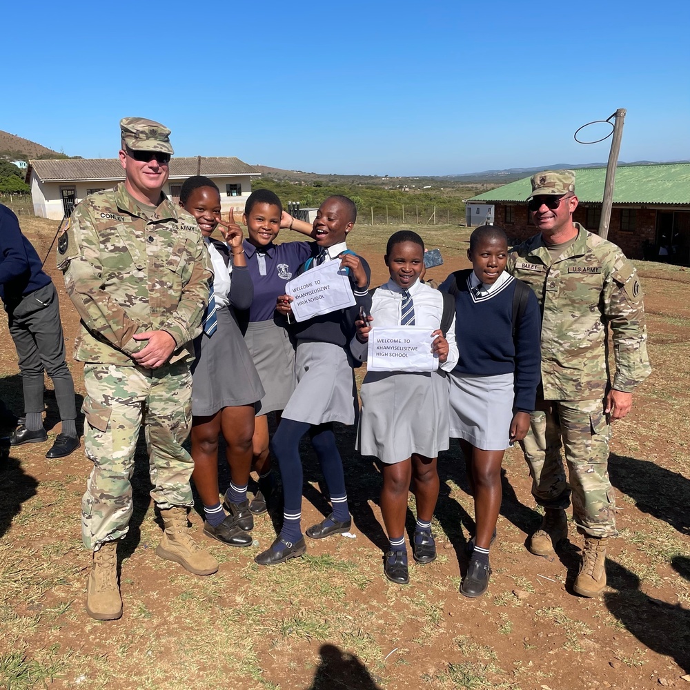 
                Lt. Col. Joseph Conley and Staff. Sgt. David Bailey stand with students from the Khanyiselisizwe High School for Nelson Mandela International Day on July 18, 2022. The U.S. Soldiers are there for Shared Accord, a biannual training event to enhance operational skills and partnership between the United States and South Africa.

Note: The Khanyiselisizwe High School kindly permitted photographs to be taken during the Mandela Day activities and gave consent for their publication.            
