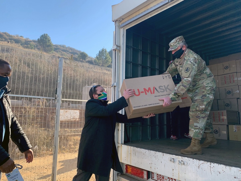 
                U.S. Army Maj. Todd Meskil, the U.S. Embassy Army Attache assigned in Pretoria, South Africa, passes protective equipment supplies to Rudolph Stroebel, the South African High Commission Maseru First Secretary during a supply transfer at the Maseru Bridge Border Post crossing between South Africa and the Kingdom of Lesotho on June 25, 2020. Military personnel assigned to the U.S. embassy in South Africa delivered 12,000 medical grade face masks, 11,000 face shields and 256 thermometers to their counterparts from the U.S. embassy in the Kingdom of Lesotho. (U.S. National Guard photo by Lt. Col. Alvin Phillips, New York National Guard)            